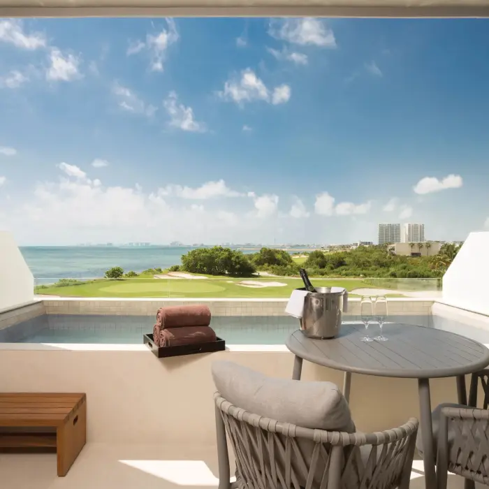 Balcony setup with two chairs and ocean view, offering a serene and private outdoor escape for two guests.