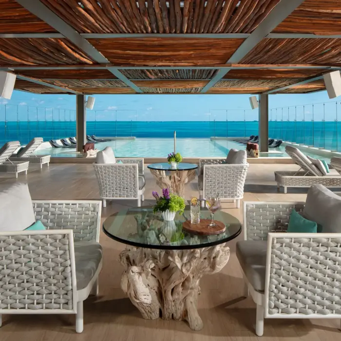 Rooftop pool lounge with lounge chairs and glass railing offering sweeping views of the Caribbean Sea.