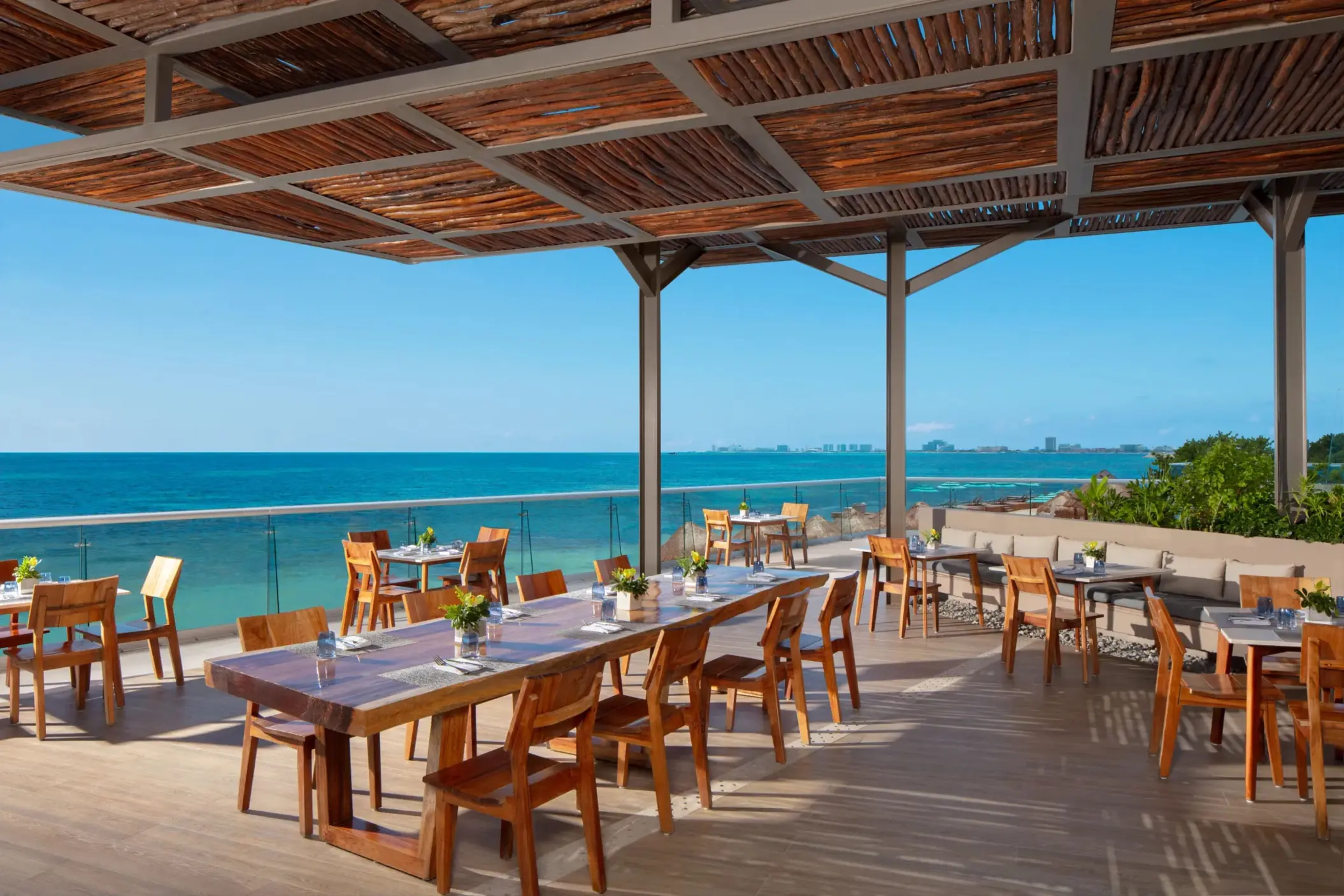 Oceanfront dining area with wooden tables and stunning turquoise sea views.