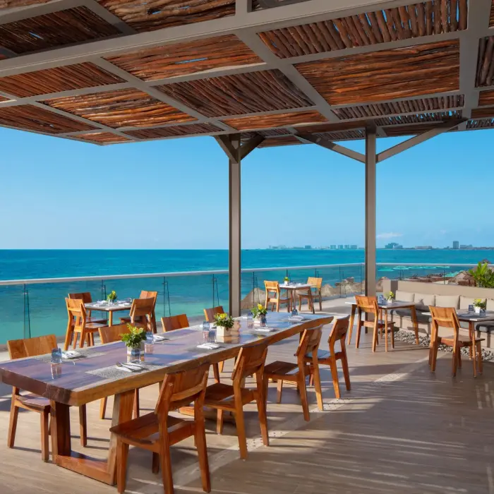 Oceanfront dining area with wooden tables and stunning turquoise sea views.