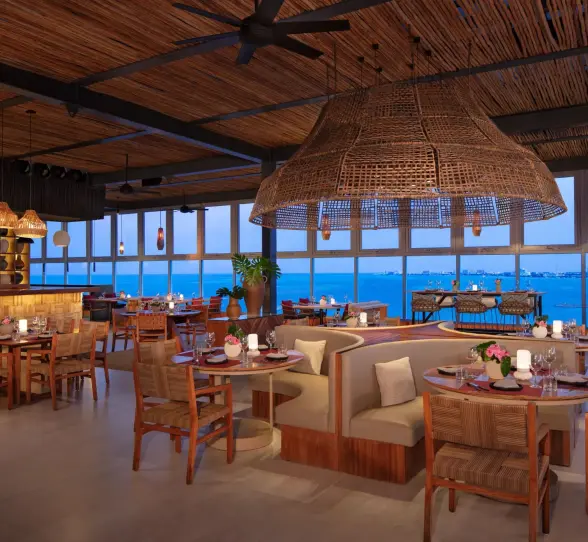 Chic restaurant interior with round booths, woven ceiling and views of Cancun skyline.