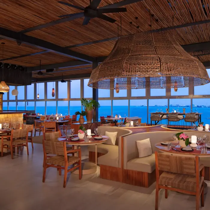 Chic restaurant interior with round booths, woven ceiling and views of Cancun skyline.