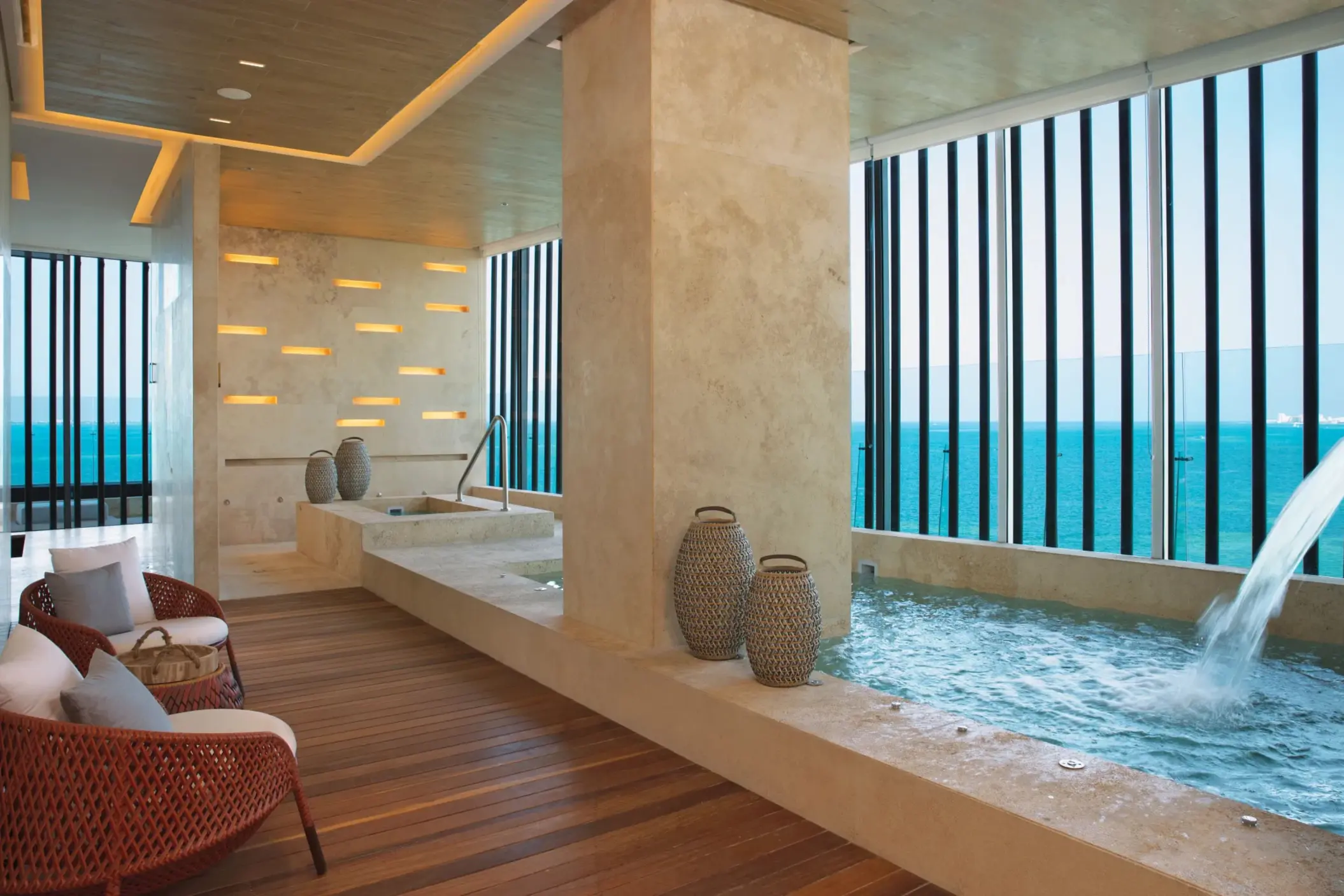 Indoor hydrotherapy area with ocean-facing plunge pool and waterfall feature.