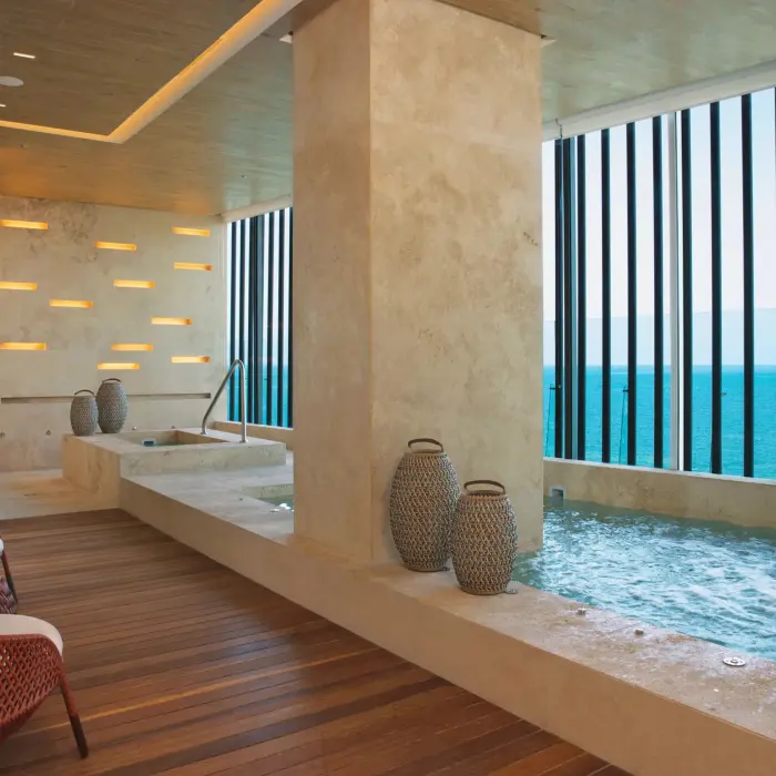 Indoor hydrotherapy area with ocean-facing plunge pool and waterfall feature.