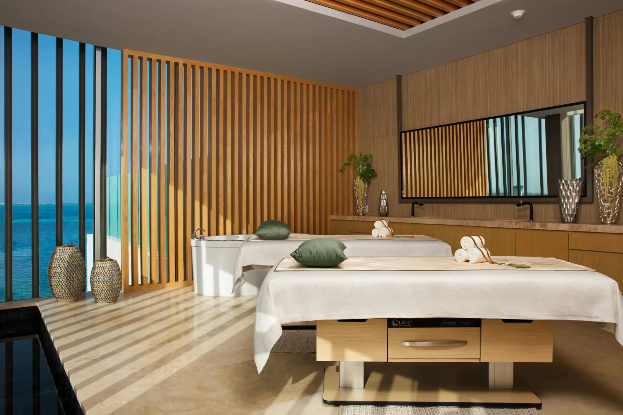 Oceanview couples’ massage room with treatment beds and wooden decor.