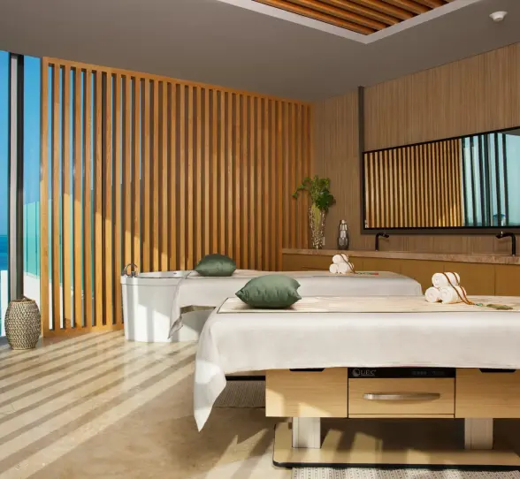 Oceanview couples’ massage room with treatment beds and wooden decor.