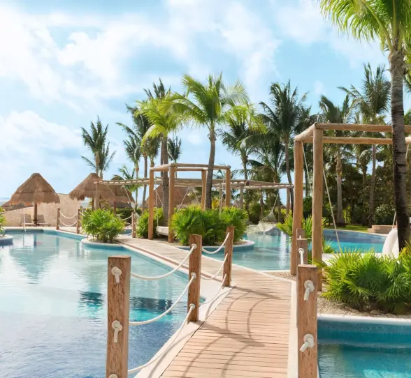 Scenic oceanfront view with lounge chairs and palm trees at a top-rated all-inclusive resort in Cancun.