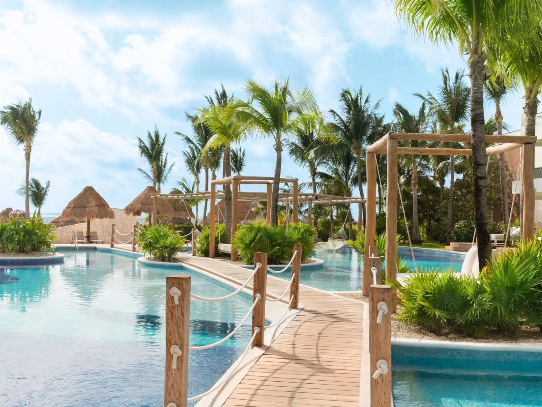 Scenic oceanfront view with lounge chairs and palm trees at a top-rated all-inclusive resort in Cancun.