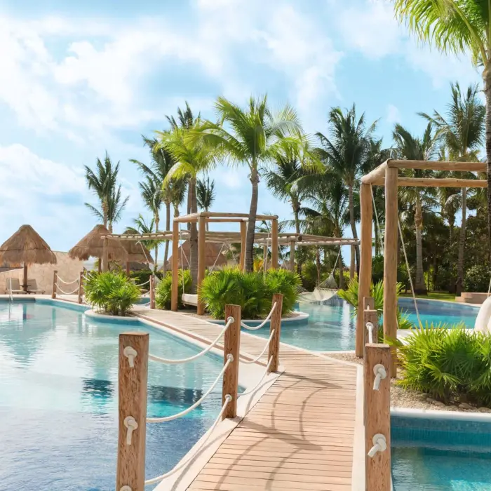 Scenic oceanfront view with lounge chairs and palm trees at a top-rated all-inclusive resort in Cancun.