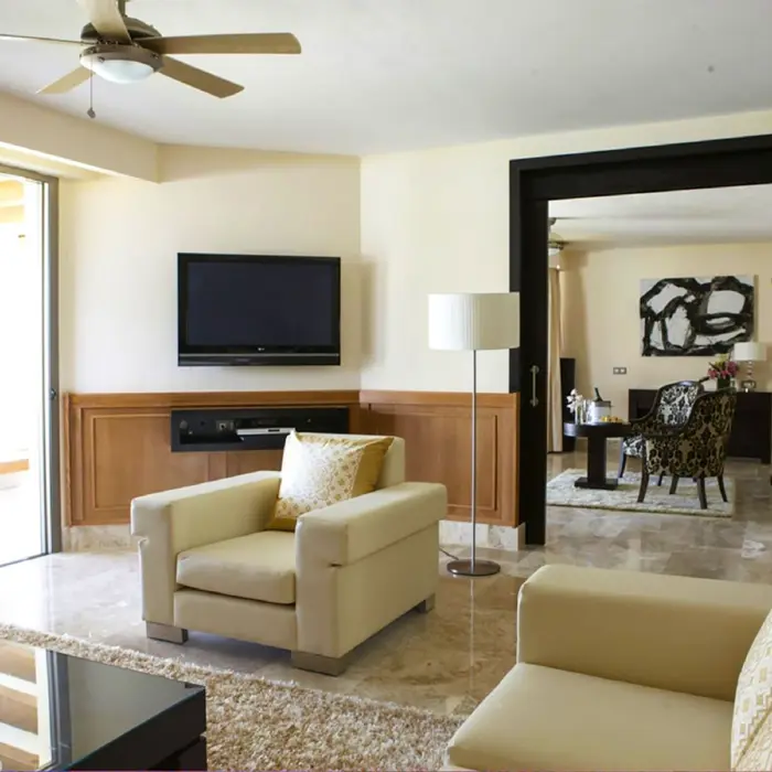 Spacious honeymoon suite living area with modern seating, marble floors, and flat-screen TV in Cancun.