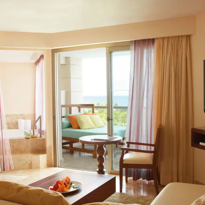 Junior suite with a private terrace, soaking tub, sheer curtains, and ocean views beyond the sliding doors.