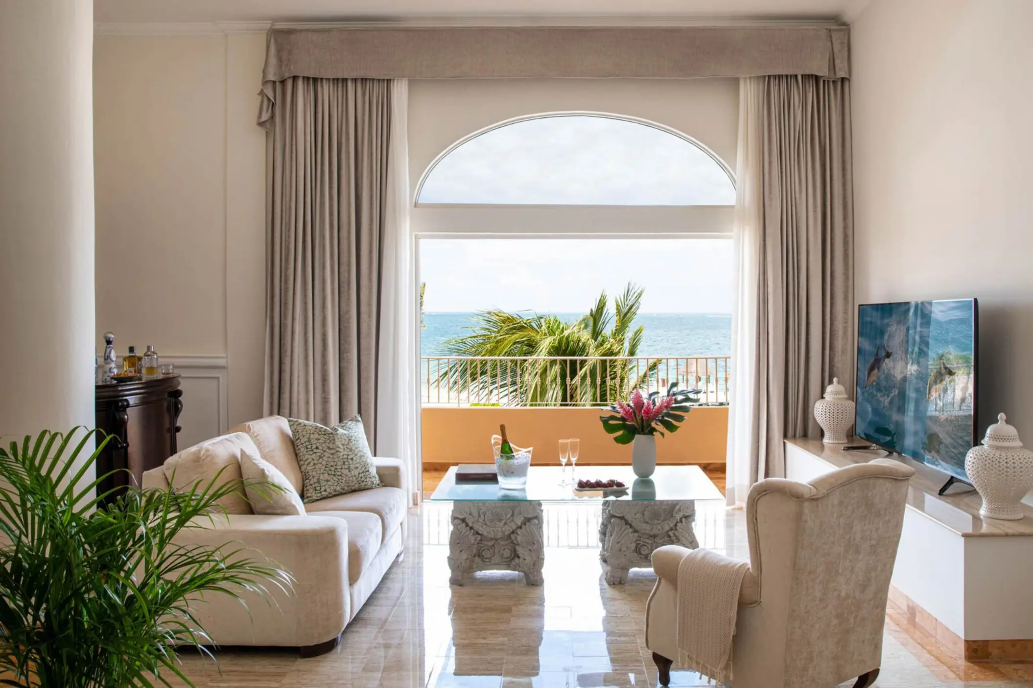 Spacious oceanview living room suite with upscale decor, elegant furnishings, and balcony overlooking tropical sea.