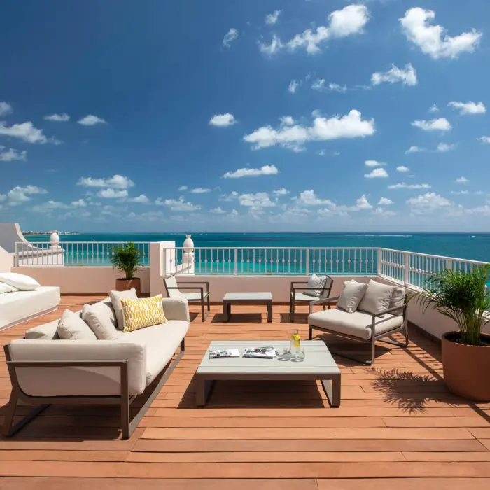 Spacious rooftop terrace with ocean views, modern lounge seating, and sunny blue skies above turquoise waters.