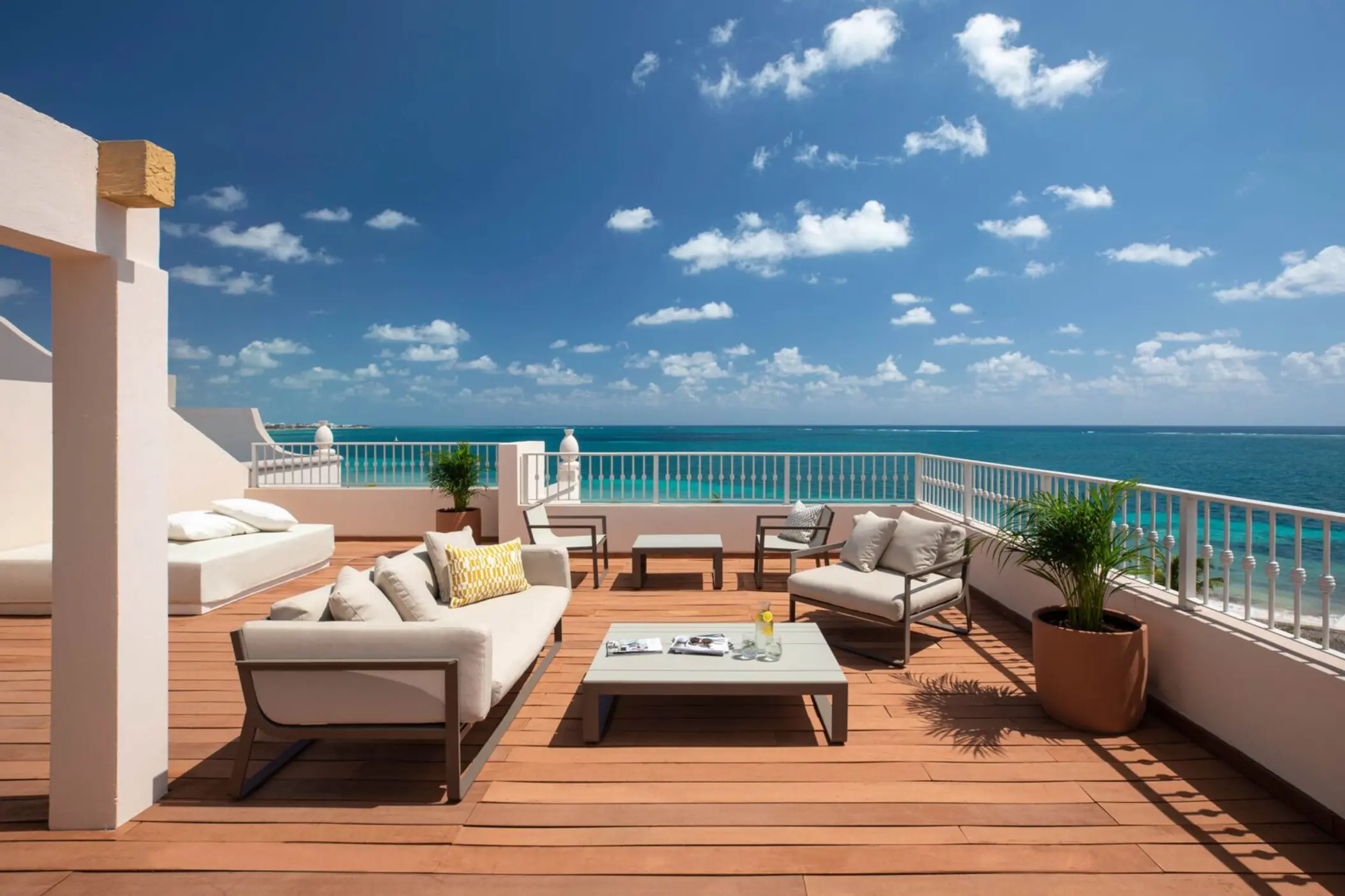 Spacious rooftop terrace with ocean views, modern lounge seating, and sunny blue skies above turquoise waters.