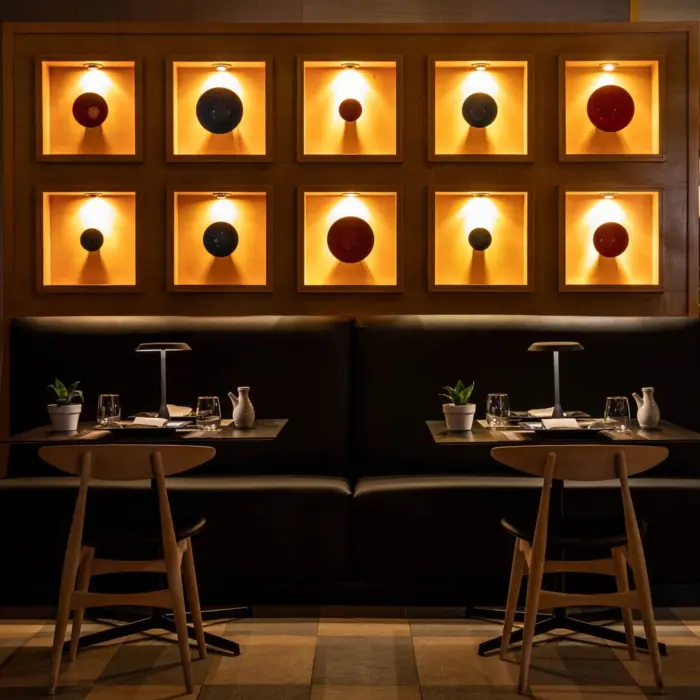 Elegant Asian restaurant interior with warm lighting, minimalist decor, and illuminated art wall display.