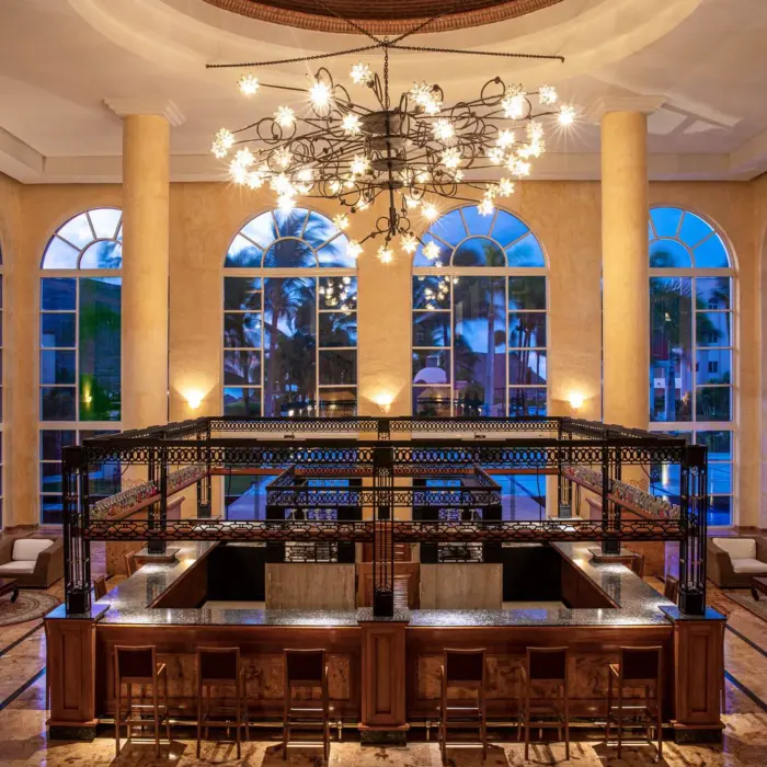 Sophisticated resort lobby bar with high ceilings, arched windows, modern chandelier, and elegant seating area.