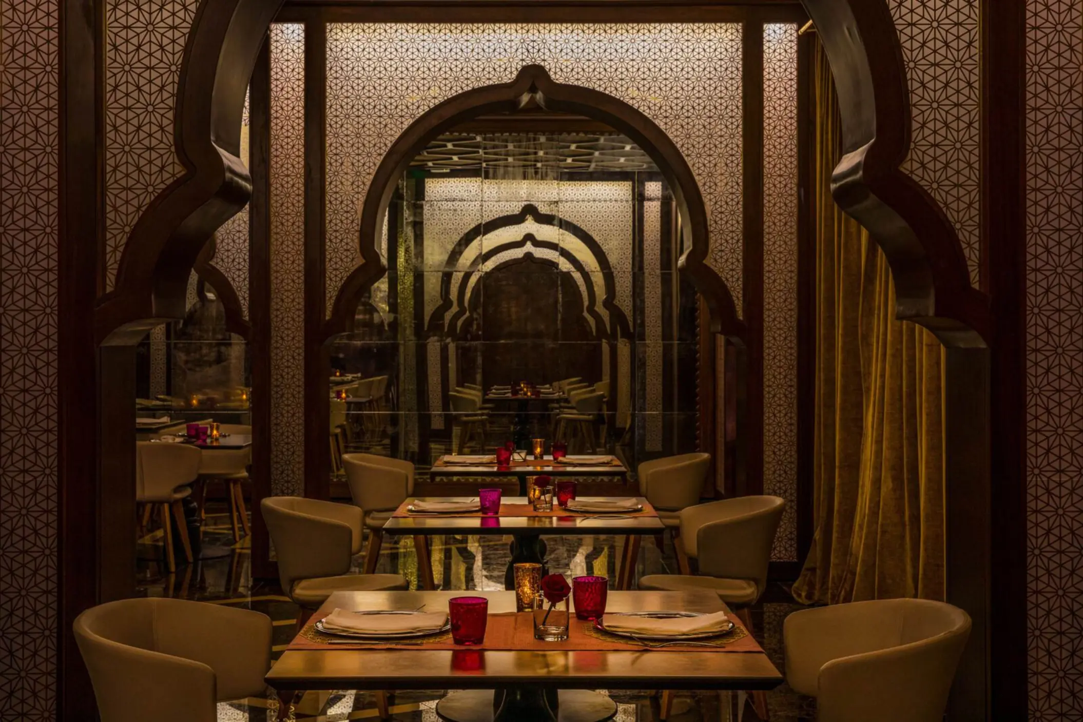 Upscale Indian restaurant with archway designs, patterned walls, and candle-lit tables for fine dining.