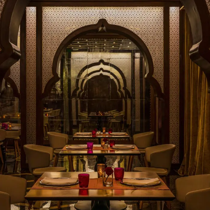 Upscale Indian restaurant with archway designs, patterned walls, and candle-lit tables for fine dining.