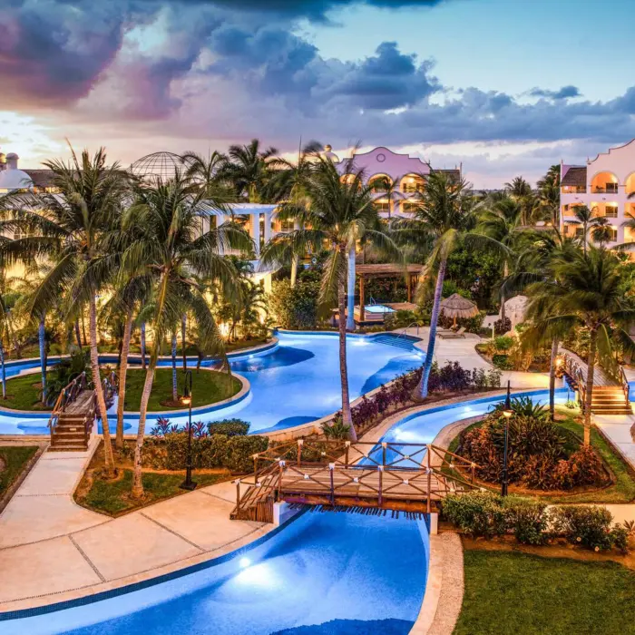 Resort domes and architecture glowing at dusk under a soft pink and lavender sky during a peaceful sunset.