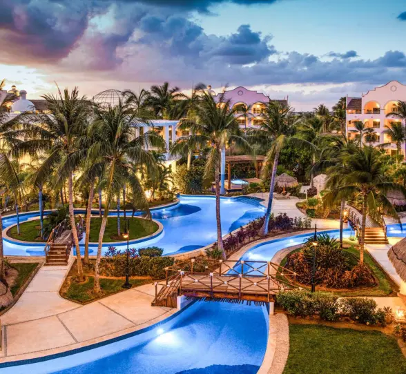 Resort domes and architecture glowing at dusk under a soft pink and lavender sky during a peaceful sunset.