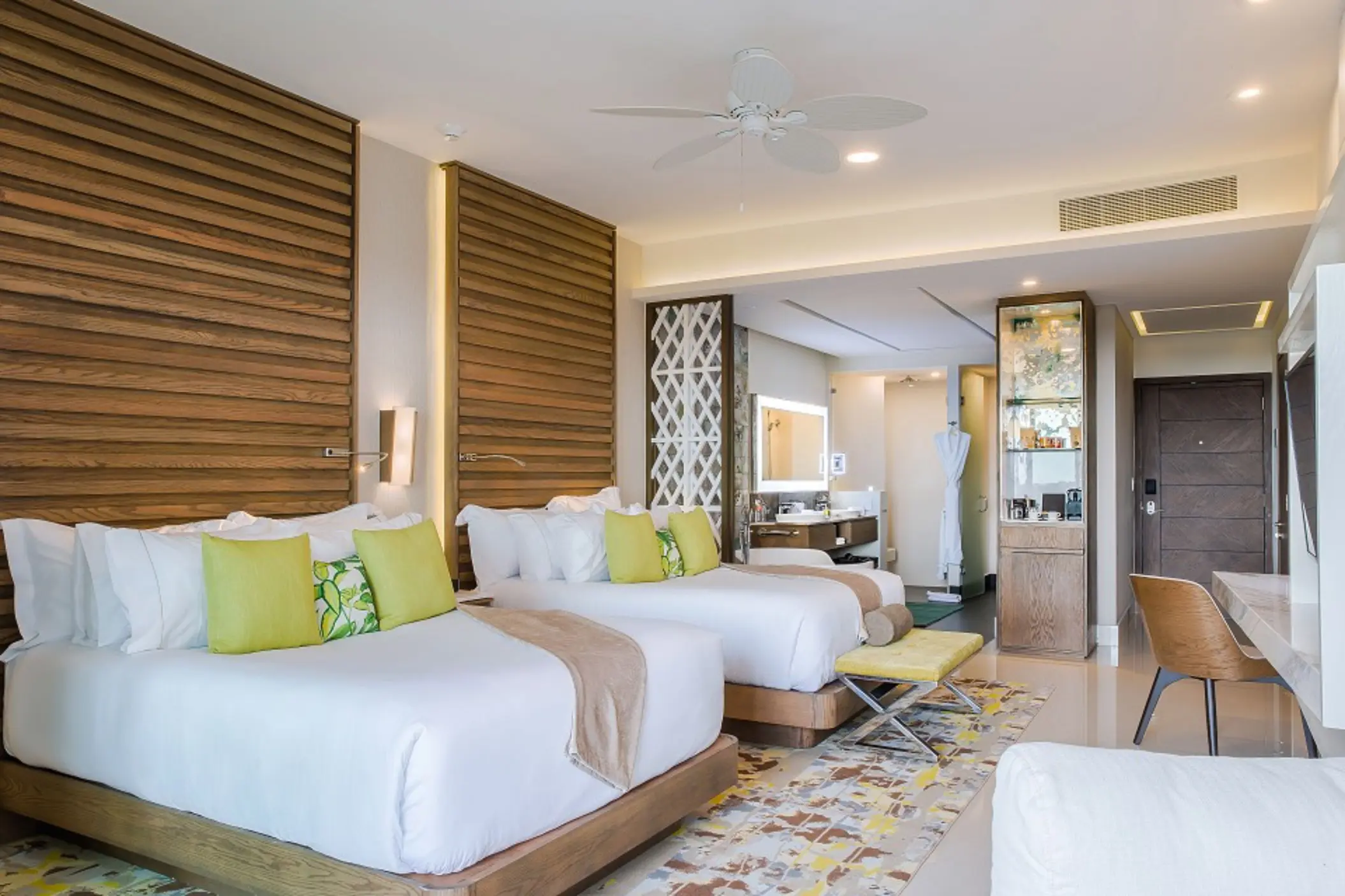 Spacious double room with two queen beds, wooden accents, and access to a modern open-plan bathroom.