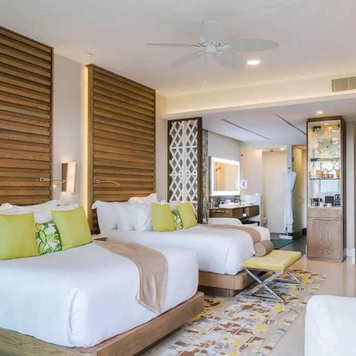 Spacious double room with two queen beds, wooden accents, and access to a modern open-plan bathroom.