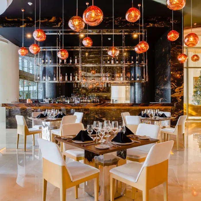 Elegant steakhouse with amber pendant lighting, black marble details, and a stylish bar and dining area.