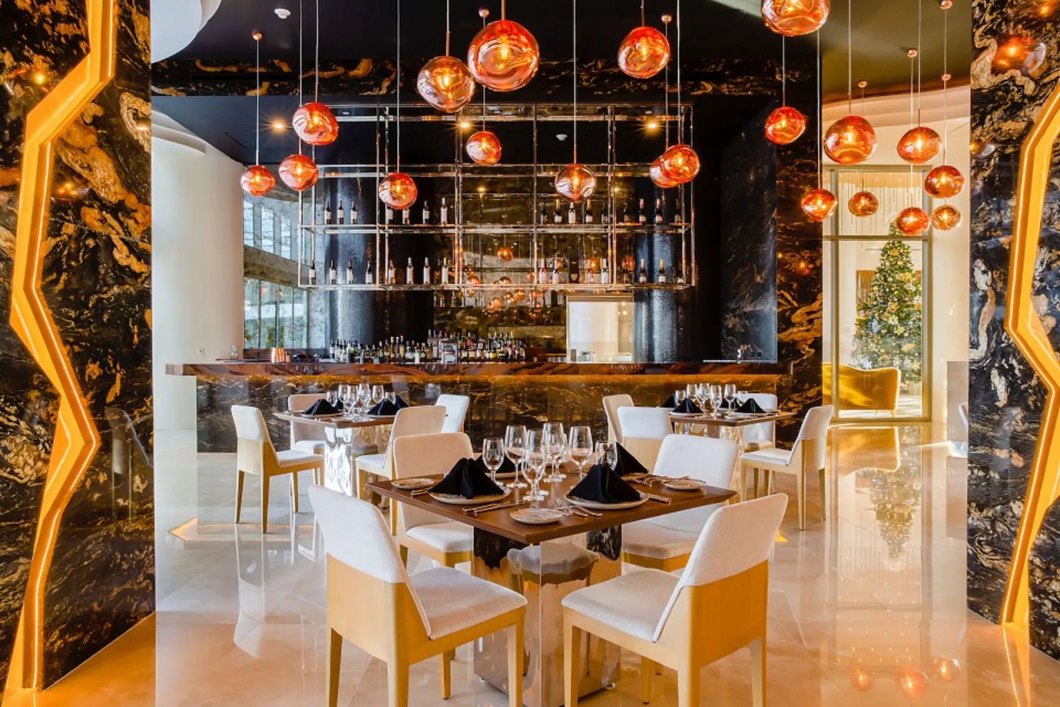Elegant steakhouse with amber pendant lighting, black marble details, and a stylish bar and dining area.