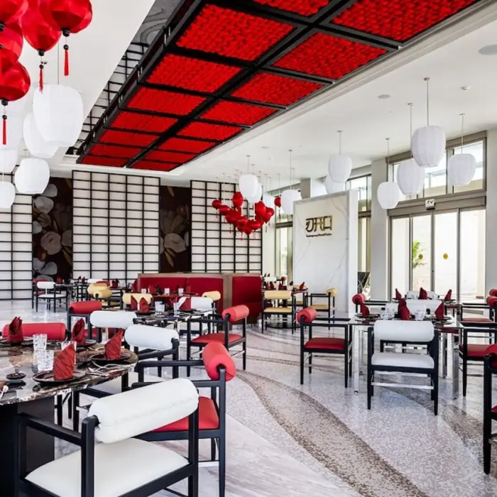 Modern Asian-inspired restaurant with red and white lanterns, bold ceiling design, and black marble tables.