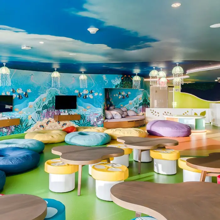 Colorful kids club with underwater-themed wall art, bean bags, jellyfish lights, and playful seating areas.