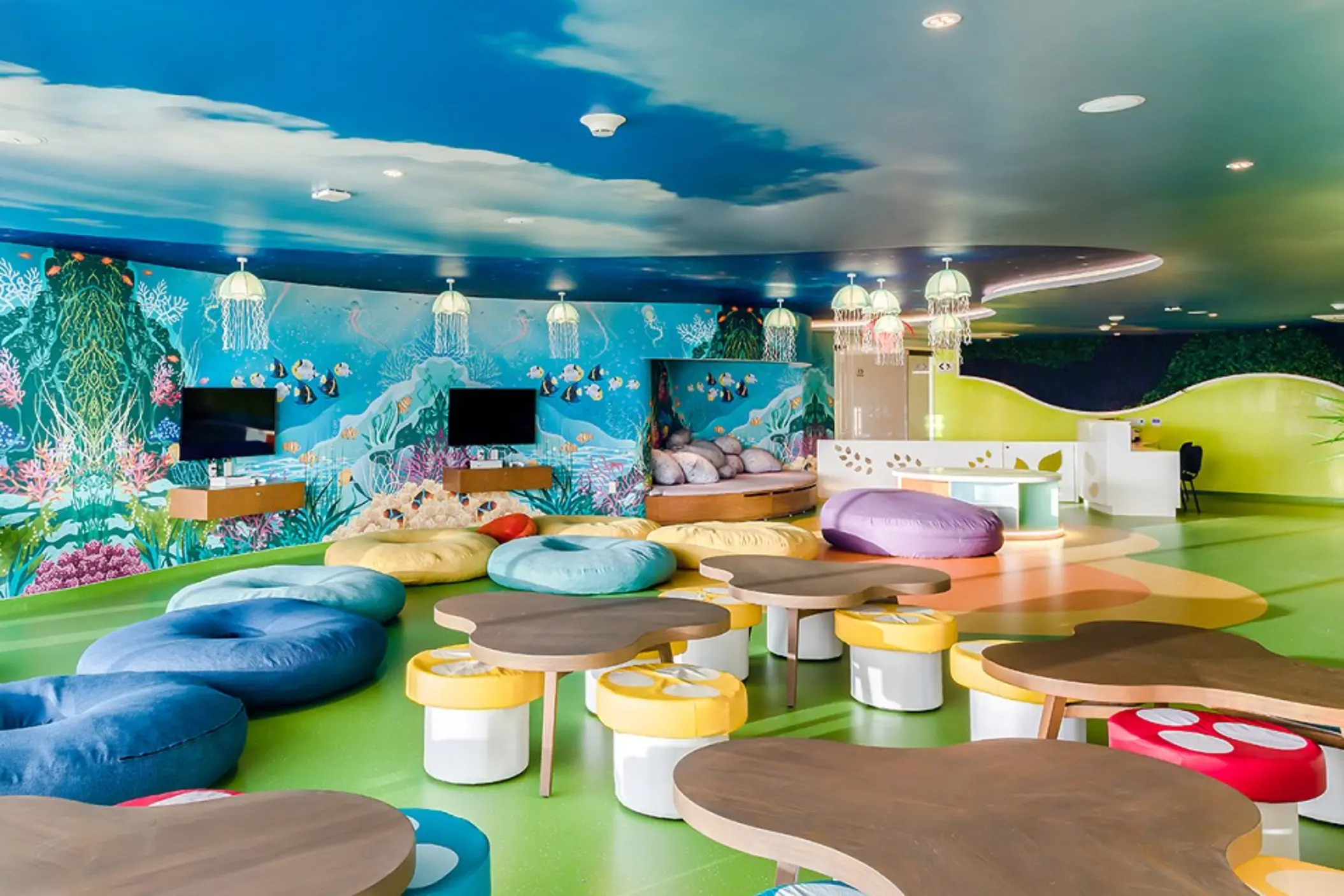 Colorful kids club with underwater-themed wall art, bean bags, jellyfish lights, and playful seating areas.