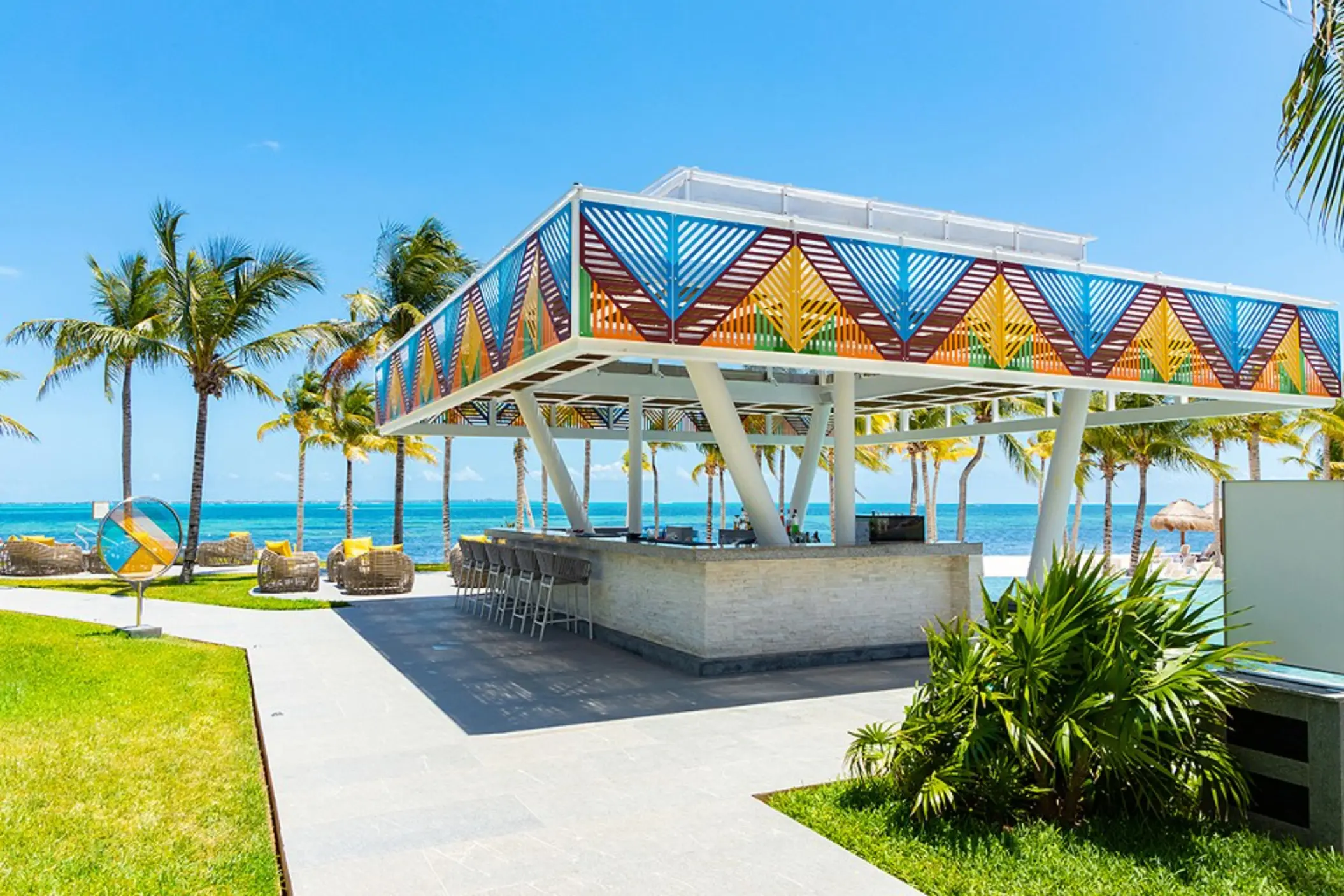 Bar with lounge seating, panoramic ocean views, and sun-soaked deck with umbrellas.