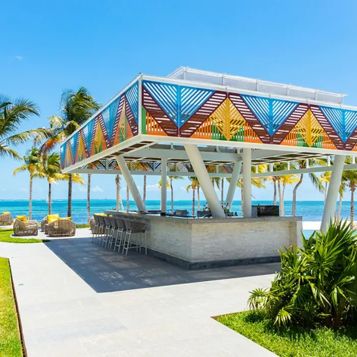 Bar with lounge seating, panoramic ocean views, and sun-soaked deck with umbrellas.