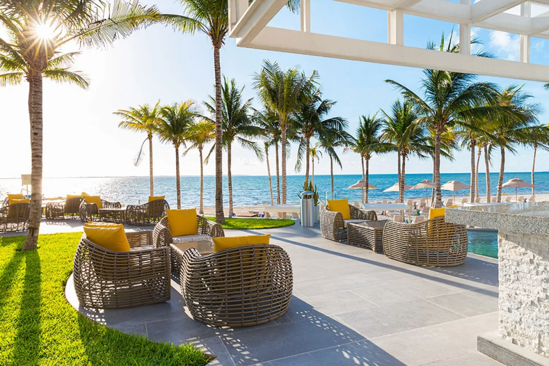 Palm-lined pool deck with ocean views, sunbeds, and shaded lounge areas at Garza Blanca Cancun.