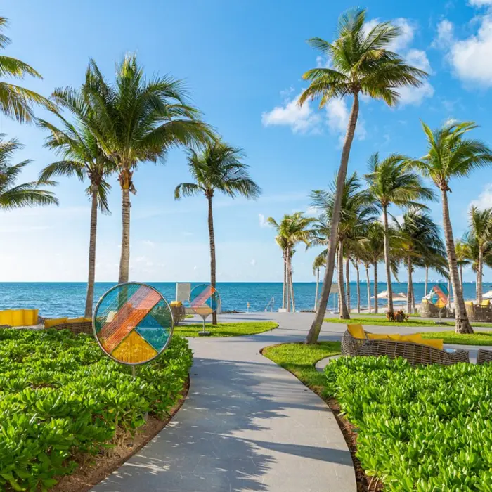 Resort pool with stone steps, tropical landscaping, and views of the Caribbean Sea in the background.