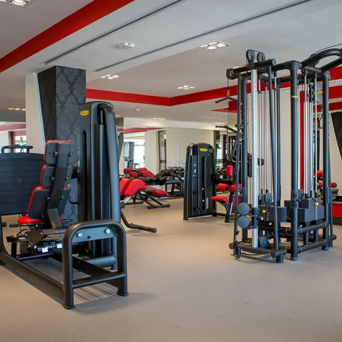 Open gym space with cardio equipment, resistance machines, and tropical greenery visible through the windows.