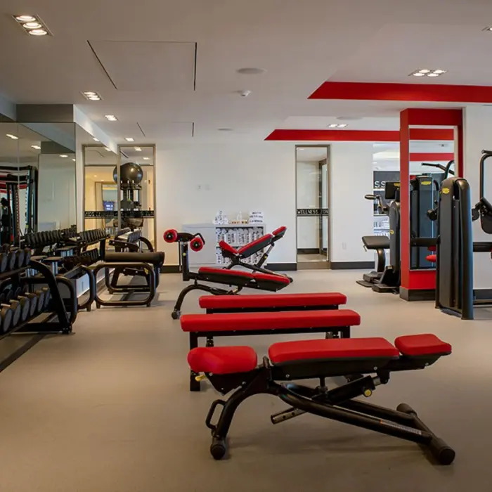 Fitness area with weights, kettlebells, and mirrors, set in a bright space with sleek flooring and lighting.