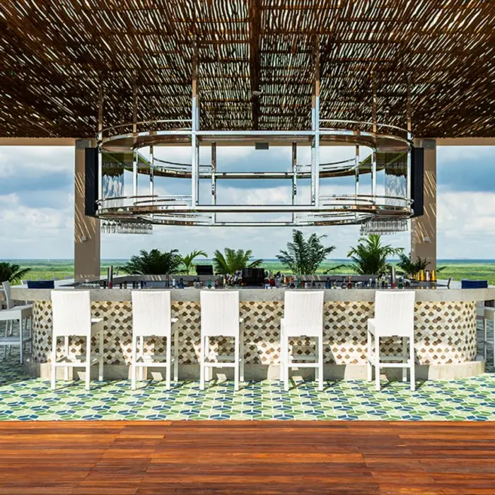 Chic rooftop bar with modern seating, open-air layout, and panoramic sunset views over the Caribbean Sea.