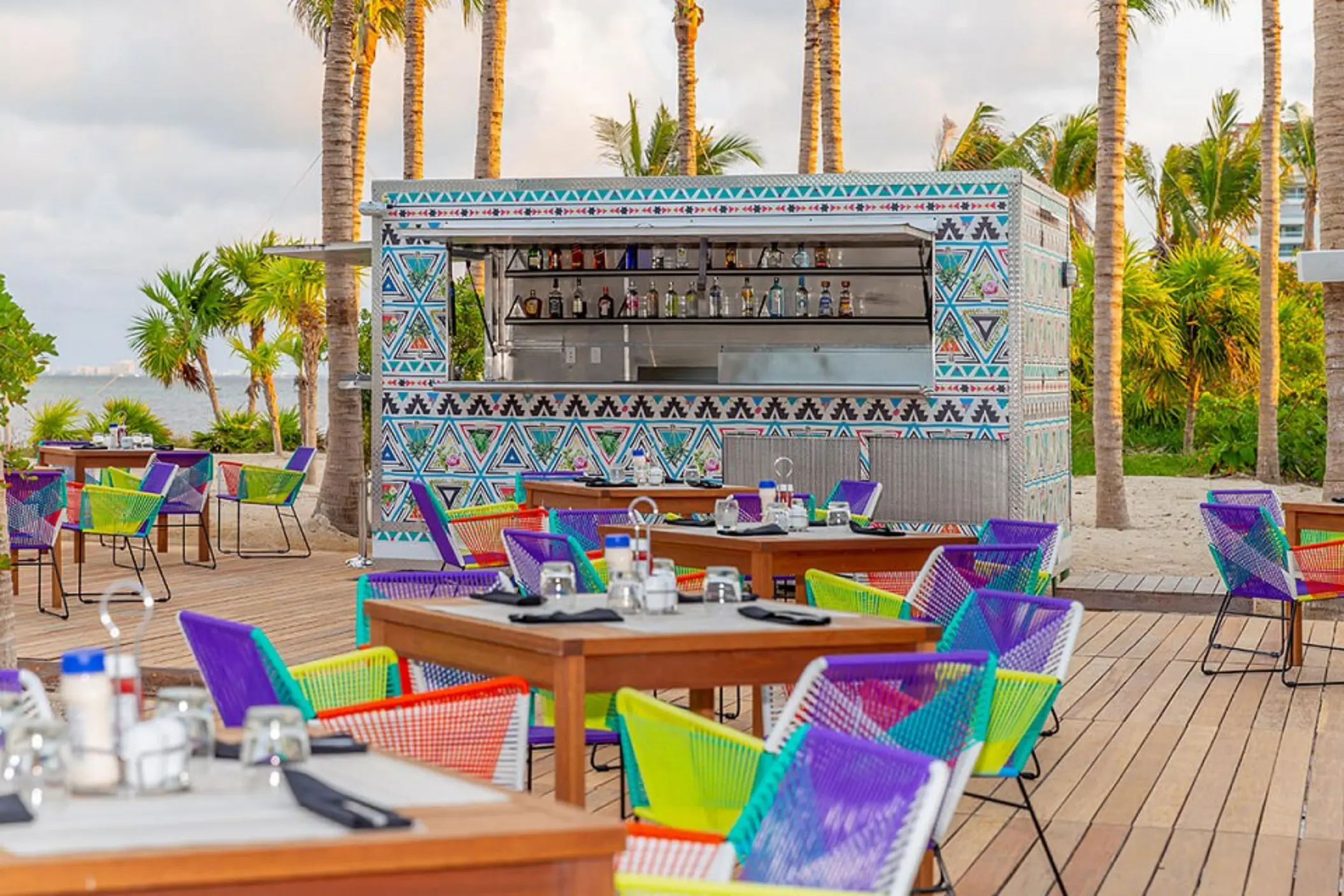 Casual poolside snack bar with turquoise tile decor, shaded seating, and colorful grab-and-go food options.