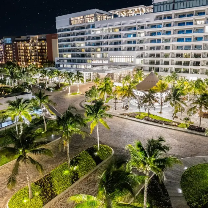 Aerial view of the full resort grounds with multiple pools, palm trees, and a beachfront lined with loungers.
