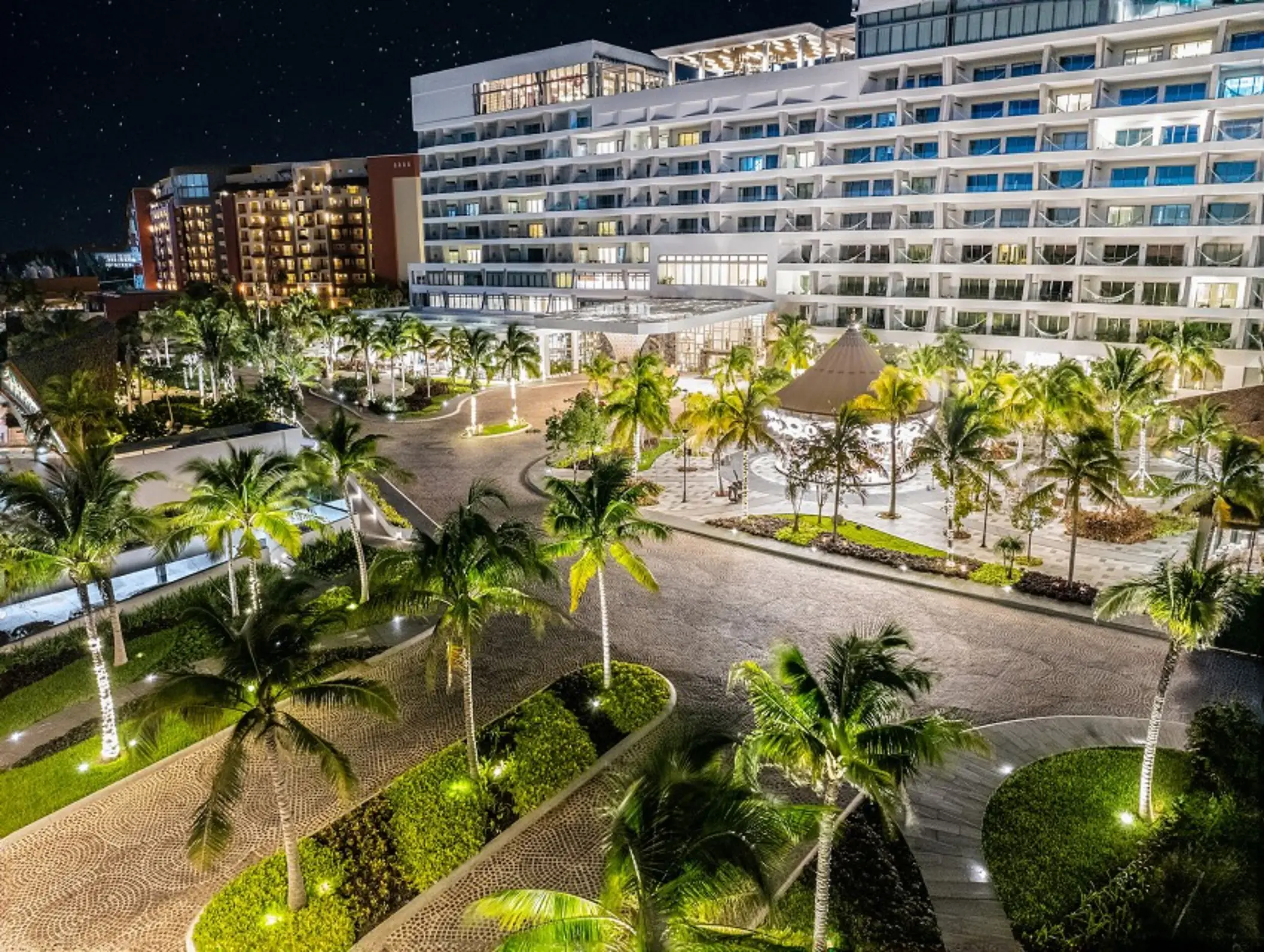 Aerial view of the full resort grounds with multiple pools, palm trees, and a beachfront lined with loungers.
