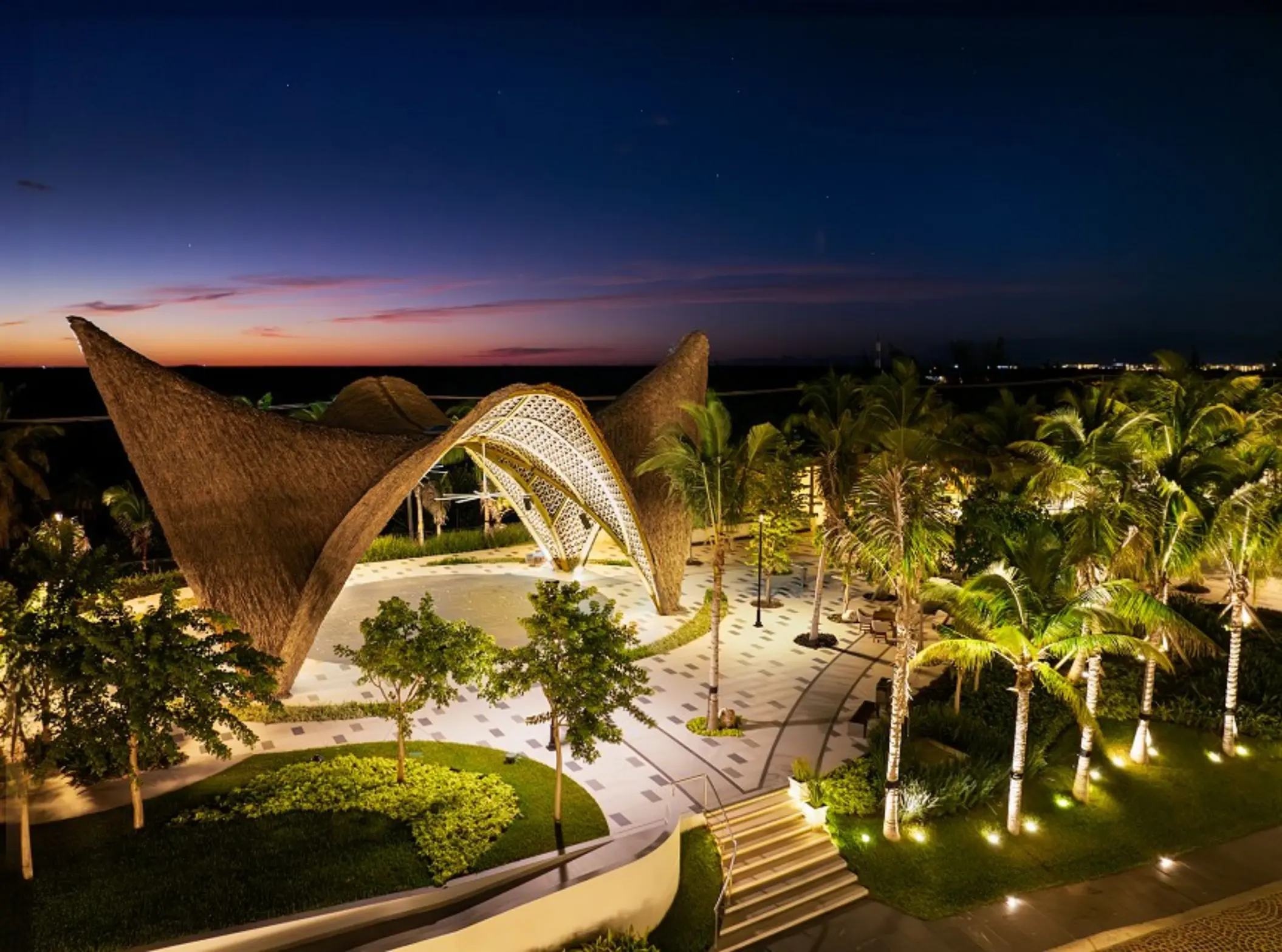 Bird’s-eye view of Garza Blanca Cancun showing curved architecture and beach with umbrellas and lounge beds.