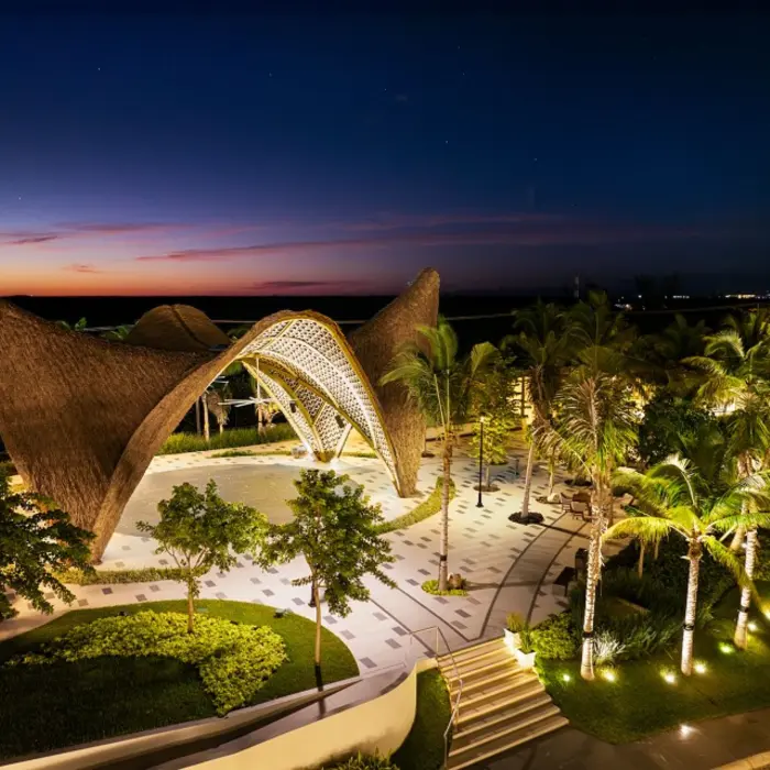 Bird’s-eye view of Garza Blanca Cancun showing curved architecture and beach with umbrellas and lounge beds.