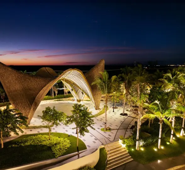 Bird’s-eye view of Garza Blanca Cancun showing curved architecture and beach with umbrellas and lounge beds.