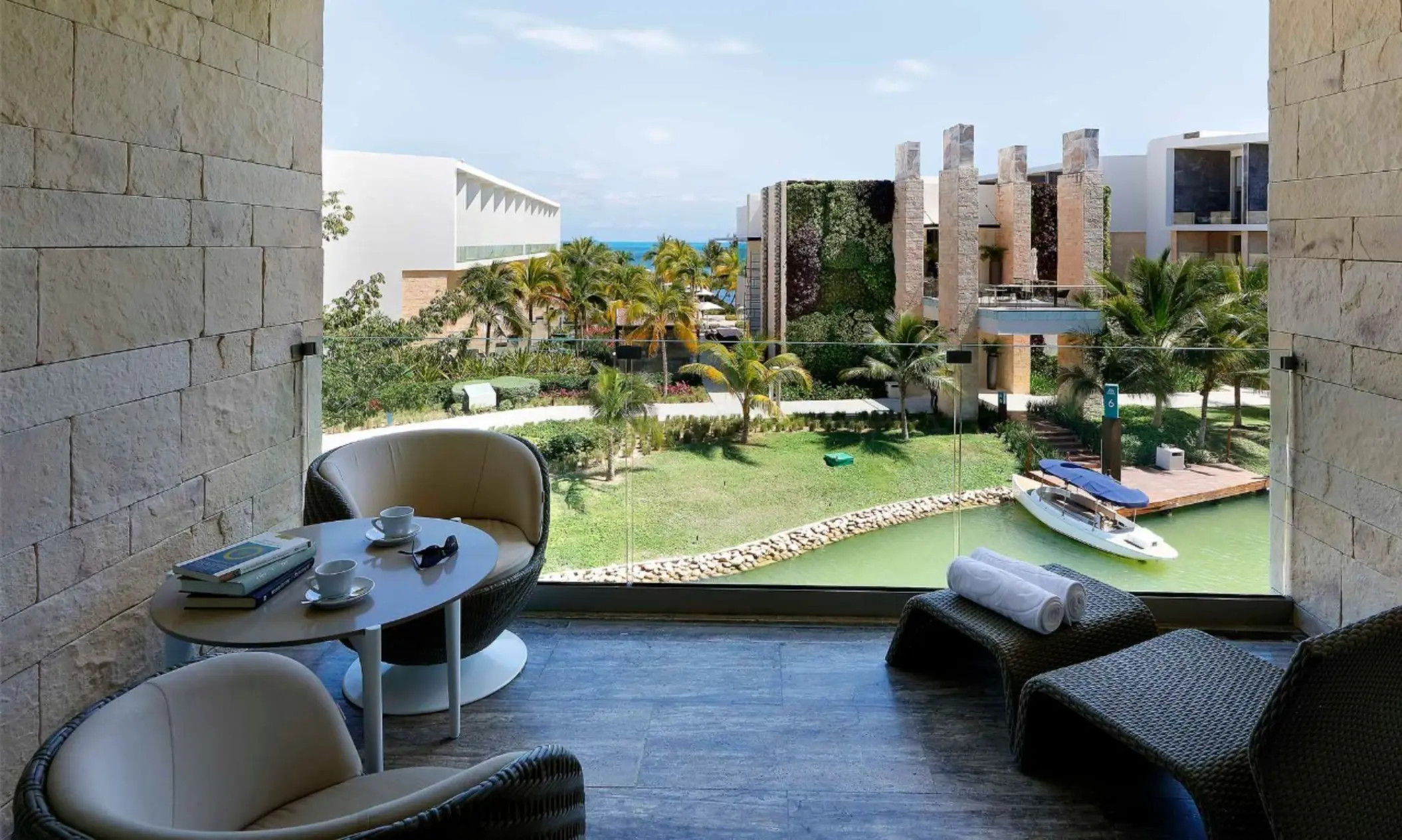 Private terrace lounge with waterway views, cozy seating, and lush greenery.