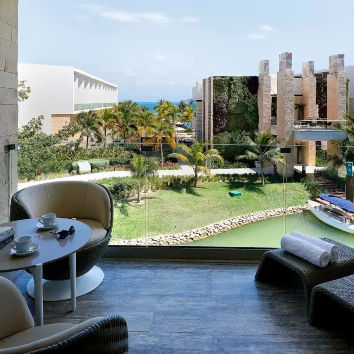 Private terrace lounge with waterway views, cozy seating, and lush greenery.