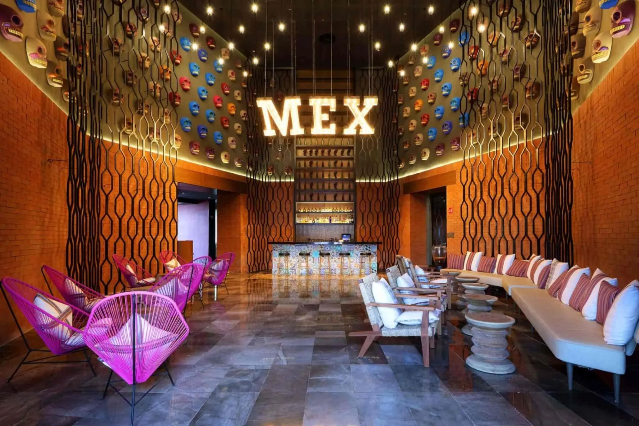 Vibrant Mexican-themed lounge bar with colorful chairs and MEX sign wall.