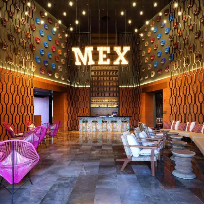 Vibrant Mexican-themed lounge bar with colorful chairs and MEX sign wall.