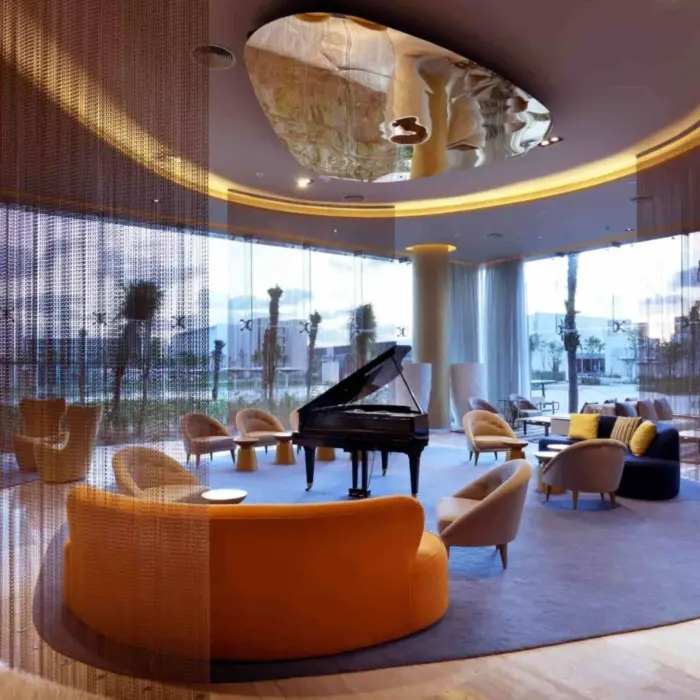 Chic hotel lobby with circular lounge seating, grand piano, and contemporary ceiling design.