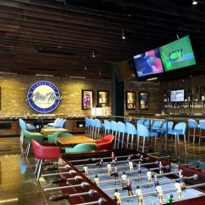 Vibrant sports bar with TVs, foosball tables, and colorful seating at Xtra Time.